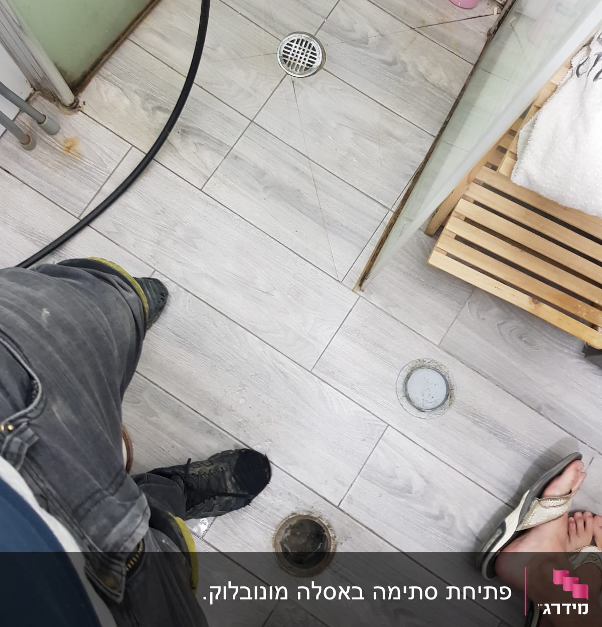 רצפת חדר אמבטיה עם פתח ניקוז פתוח וצינור עבודה